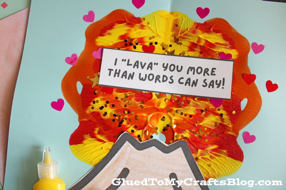 A handmade volcano craft with red, yellow, and orange paint lava, decorated with pink hearts. A sign above the volcano reads, I LAVA YOU MORE THAN WORDS CAN SAY!.