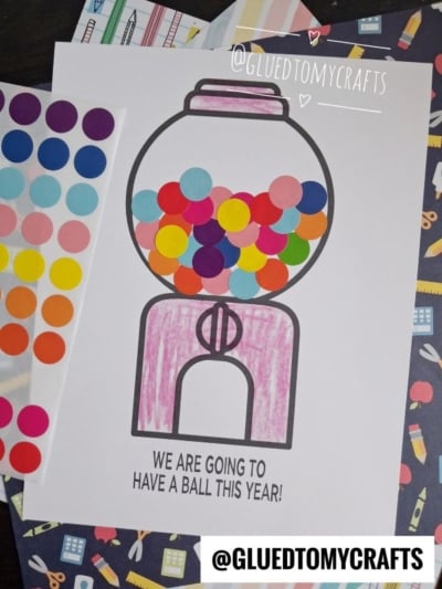 A gumball machine coloring page with colorful dot stickers as gumballs and the text “We are going to have a ball this year!” This fun gumball craft idea is surrounded by sticker sheets and crafting supplies for added creativity.