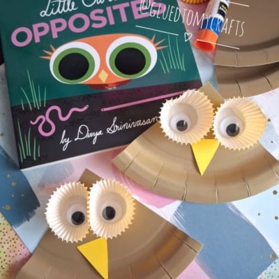 Children’s book “Little Owl’s Opposites” next to two owl crafts made from paper plates, googly eyes, and cupcake liners. Glue sticks and colored paper are also visible. @GLUEDTOMYCRAFTS watermark is over the image.