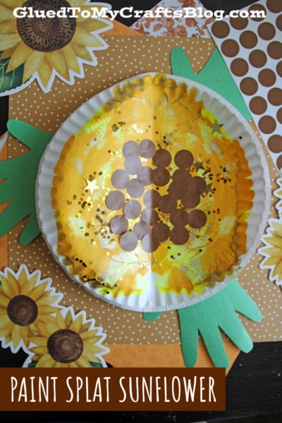 A paper plate decorated with yellow paint, brown dots, and gold glitter to resemble a sunflower, set on a background with sunflower images, green paper leaves, and brown polka dots. Text: PAINT SPLAT SUNFLOWER.