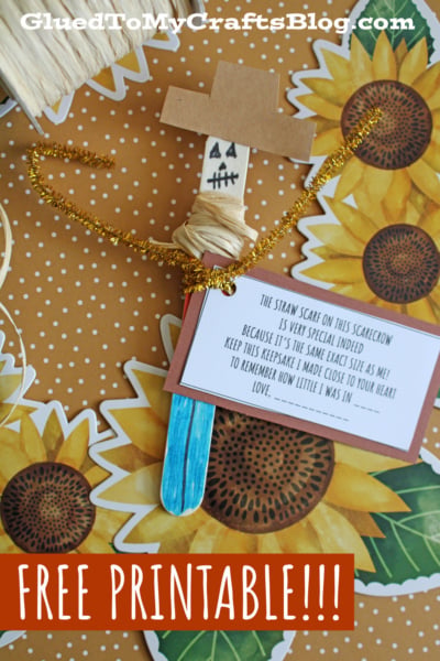 A handmade scarecrow craft with a popsicle stick, paper hat, raffia, and a gold pipe cleaner. It holds a card with a poem, surrounded by sunflower decorations. Text reads, FREE PRINTABLE!!! and GluedToMyCraftsBlog.com.