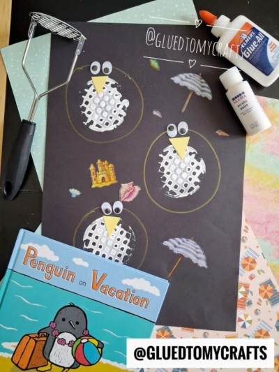 A craft project with four penguins made from white mesh on black paper, this potato masher stamped craft is surrounded by glue, a potato masher, papers, and the book Penguin on Vacation. Stickers of a sandcastle and umbrella are also placed nearby.