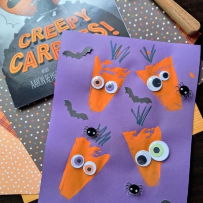 Purple paper with orange carrot shapes, googly eyes, and drawn green stems, plus small paper bats and spiders; a Creepy Carrots! book, a pie server stamped with fun details, spatula, and polka dot paper are also visible. @GLUEDTOMYCRAFTS is at the bottom.