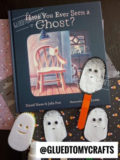 Childrens book Have You Ever Seen a Ghost? with three handmade ghost crafts featuring googly eyes and a craft stick, arranged on Halloween-themed paper—perfect inspiration for Halloween Crafts for Kids. Instagram handle @GLUEDTOMYCRAFTS is included.