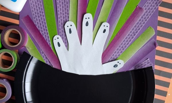 A Halloween craft shows paper ghost hands in a black paper cauldron with green and purple strips, Elmers glue, washi tape, and an orange-striped background. The username @GLUEDTOMYCRAFTS is displayed.