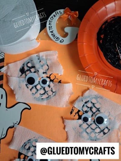 Orange paper with two mummy crafts made from white gauze strips and googly eyes, a ghost cutout, orange plate with black string, white G ornament, and rolls of toilet paper. @GLUETOMYCRAFTS appears in several places.