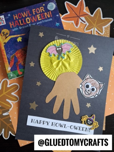 A Halloween craft features a handprint bat with cupcake liners, stars, and bat stickers on black paper, perfect for pairing with a halloween story time next to a Howl for Halloween! book and orange polka-dot paper. Text reads HAPPY HOWL-OWEEN! and @GLUEDTOMYCRAFTS.