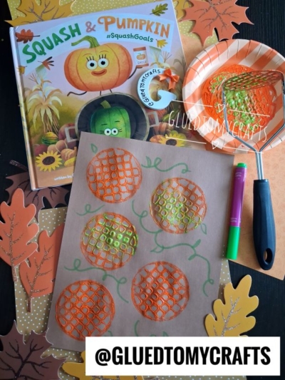 Childrens pumpkin art with orange and green paint, potato masher, plate, book Squash & Pumpkin, scattered paper leaves, and marker. This fun FALL CRAFTS FOR KIDS activity uses the potato masher to create textured patterns on brown paper while painting pumpkins.