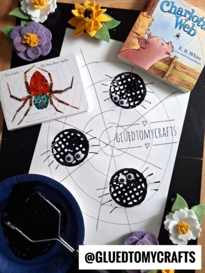 A craft project features spider faces on paper, a The Very Busy Spider book, a Charlottes Web book, felt flowers, and a black dish with paint. The Instagram handle @GLUEDTOMYCRAFTS is at the bottom.