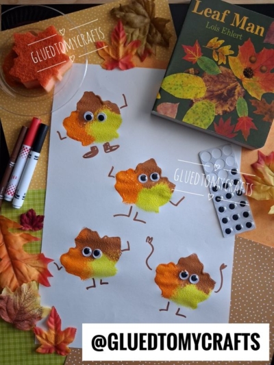 A craft table with painted leaf creatures on paper, googly eyes, markers, fake leaves, a book titled Leaf Man, and a glue dot pack—perfect inspiration for FALL CRAFTS FOR KIDS. @GLUEDTOMYCRAFTS is printed at the bottom.