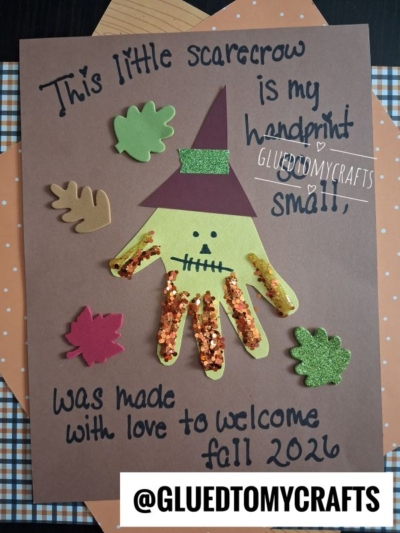A fall-themed craft, perfect for FALL CRAFTS FOR KIDS, featuring a handprint scarecrow with a hat, glitter, and leaf cutouts. Text reads: This little scarecrow is my handprint, so small, was made with love to welcome fall 2026.