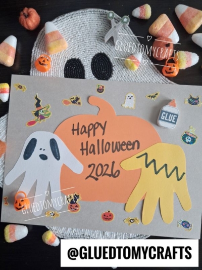 A Halloween craft features a pumpkin cutout that says Happy Halloween 2026, with ghost shapes, stickers, candy corn, and festive decorations on a ghost-shaped placemat—making it a perfect addition to your collection of FALL CRAFTS FOR KIDS. The Instagram handle @GLUEDTOMYCRAFTS appears at the bottom.