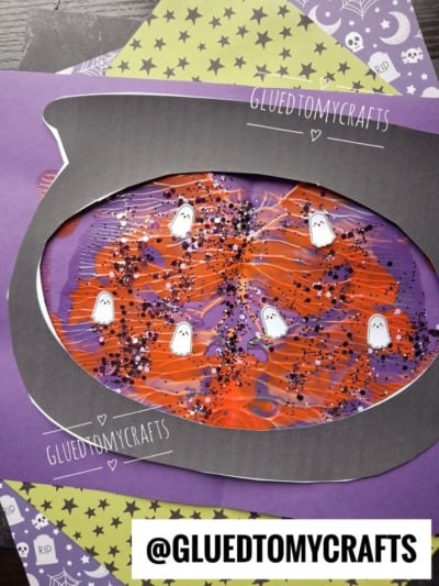 A Halloween-themed PAINT SPLAT CRAFT with a cauldron cutout, orange and purple paint, glitter, and ghost stickers on layered papers. The handle @GLUEDTOMYCRAFTS appears at the bottom.