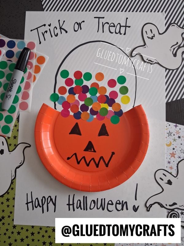A pumpkin-themed Halloween craft made with an orange paper plate, colorful dot stickers, and ghost drawings on white paper that says Trick or Treat and Happy Halloween!.