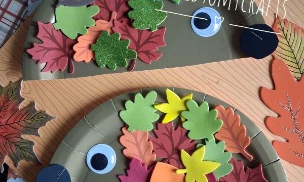 Two paper plates decorated as hedgehogs with big googly eyes and colorful foam leaves. They are on a leaf-patterned background with the text @GLUEDTOMYCRAFTS and GLUEDTOMYCRAFTS visible.