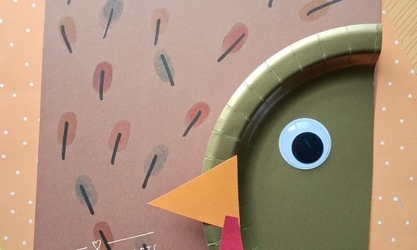 A turkey craft made from brown paper, a gold paper plate, a googly eye, orange beak, and red wattle, with @GLUETOMYCRAFTS text labels and a star-patterned background.