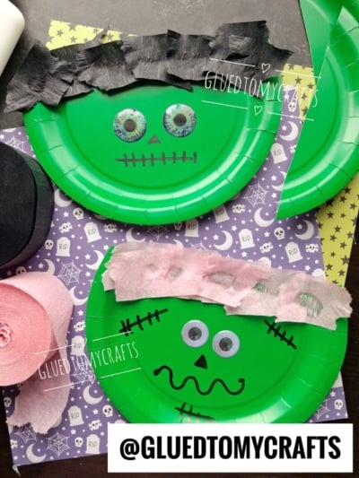 Two green paper plates decorated as Frankenstein faces with googly eyes, paper hair, and marker details resemble a fun paper plate zombie craft on patterned backgrounds with stars and Halloween motifs.