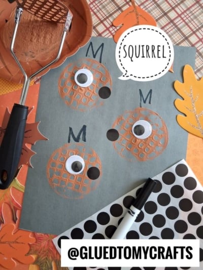 A gray paper shows three round orange squirrel faces made with a potato masher, googly eyes, and black marker noses. Craft supplies and @GLUEDTOMYCRAFTS label are included.