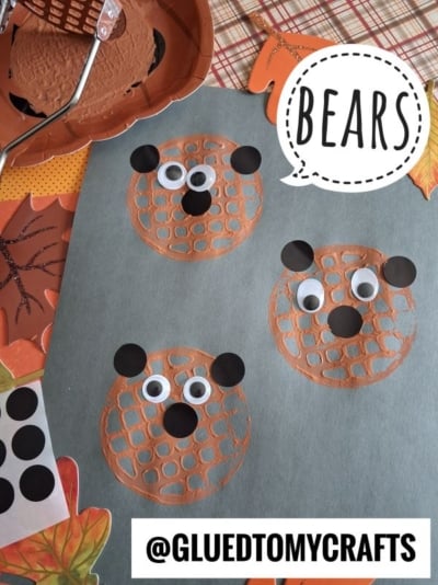 Three bear faces made from painted waffle prints with googly eyes and black paper ears on blue paper. Autumn leaves and a waffle maker are visible. Text reads BEARS and @GLUEDTOMYCRAFTS..