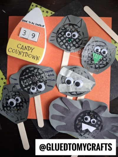 Six Halloween Crafts for Kids made with black paper, googly eyes, and popsicle sticks are displayed on an orange background, along with a candy corn countdown cutout reading CANDY COUNTDOWN 39 and the text @GLUEDTOMYCRAFTS.