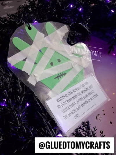 A paper handprint craft decorated with white tape to look like a mummy, with a poem attached at the bottom.