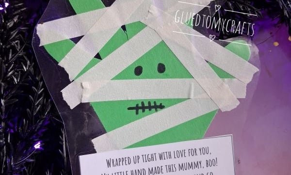 Handprint craft shaped like a mummy with white paper strips, a drawn face, and a poem about a childs handprint.