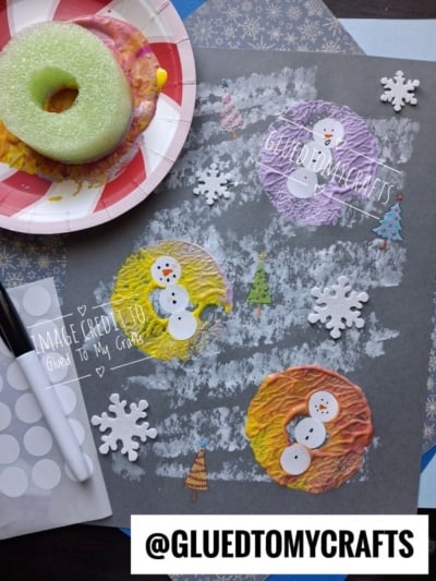 Three snowmen made from painted pool noodle prints on grey paper, decorated with foam snowflakes and small tree cutouts.