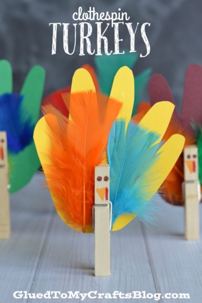 DIY turkeys made from wooden clothespins and colorful paper handprint cutouts decorated with feathers.