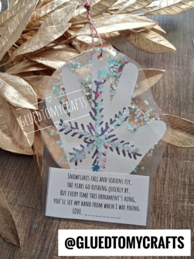 A clear plastic handprint ornament decorated with a snowflake and glitter, attached to a card with a poem about watching children grow.
