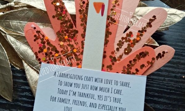 A turkey craft made from a painted popsicle stick and paper handprints covered in glitter, with an attached card that reads, A thanksgiving craft with love to share, to show you just how much I care.