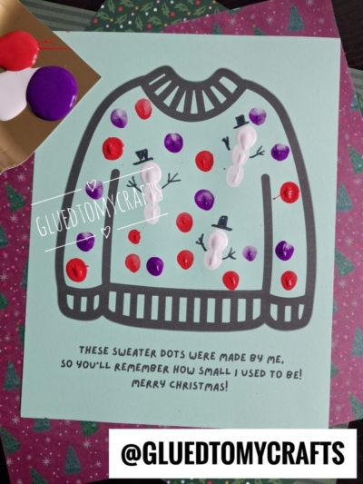 A light green sheet featuring an outline of a sweater decorated with painted dots and three small finger-painted snowmen, with text reading, These sweater dots were made by me, so youll remember how small I used to be! Merry Christmas!.