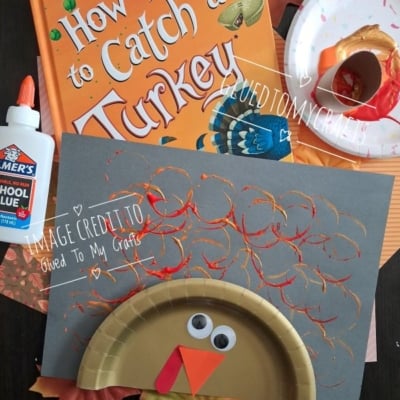 A turkey craft made from a paper plate, wiggly eyes, and orange paper, displayed with the book How to Catch a Turkey and a bottle of glue.