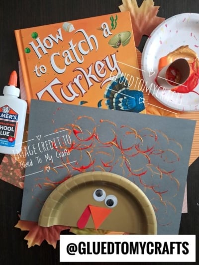 A turkey craft made from a paper plate, wiggly eyes, and orange paper, displayed with the book How to Catch a Turkey and a bottle of glue.